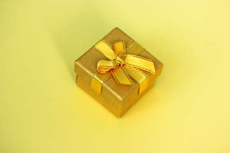 Bright yellow gift box isolated with a bow on a yellow background. Top view, flatly. Holiday background. Gift for Mother's Day, March 8, Easter, Birthday.の写真素材