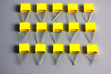 Yellow film capacitors isolated on gray background top view. Many square shape plastic electronic...