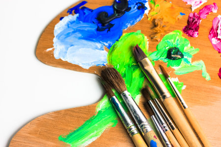 Wooden palette for mixing paints and brushes soiled with paint close-up. Creativity, art concept....
