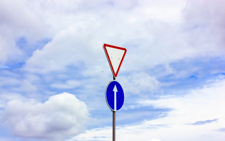 Grant right of way traffic sign against blue sky at sunny day. A priority sign telling drivers to...
