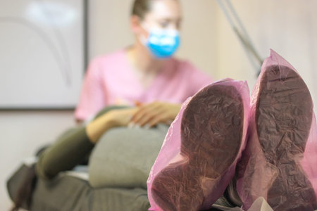 A female patient wearing pink shoe covers lies on examination couch in ultrasound diagnostic...