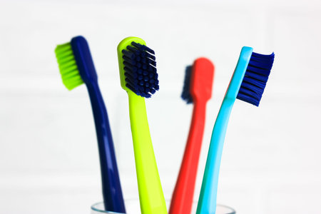 Set of plastic multicolored toothbrushes - green, blue, red, purple - in the transparent glass on a...
