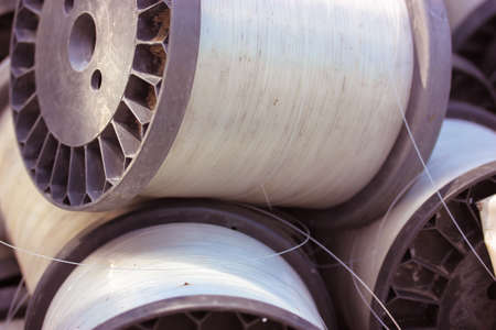 Large vintage plastic spools with sturdy transparent white fishing line close-up. Clear nylon line in roll for fishing or construction work. Fishing tackle.の写真素材