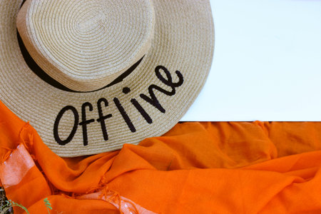 A straw hat with a written word Offline. An orange rag background, a gray laptop flatly. Lack of...