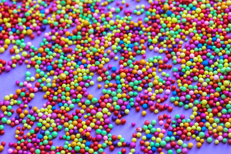 Many colorful foam balls scattered on a purple background. Round multi-color confetti backdrop....