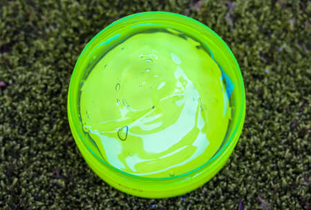 Aloe vera gel in a round jar against a green moss background top view. Green transparent liquid cream for moisturizing the body, face. Care basic no label cosmetic product. Soothes skin after sunburn.の写真素材