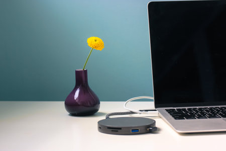 Black round adapter unit for USB HUB connection. Memory card reader connected to a gray laptop lying...
