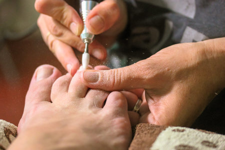 Apparatus pedicure with an electric machine in a beauty salon. Professional manicurist polishing the...