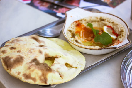 Appetizer classic hummus with olive oil, paprika, lemon, spices, green mint leaf in white ceramic...