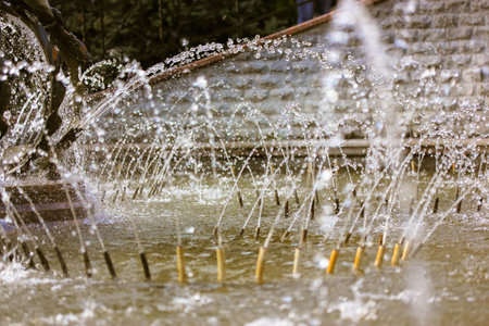 Splashing water in the fountain at summer city public urban park. Water jets abstract image close...