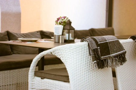 White chair on a summer patio, terrace cafe, restaurant. Checkered brown plaid on a back of a stool....