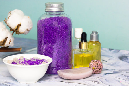 Composition with a jar of purple lavender sea salt, soap bar, cotton flower, serum oil bottles on...