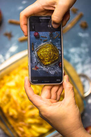 A chef taking picture of a freshly baked Thanksgiving apple pie on smartphone. Cooking, baking sweet food at home. Autumn homemade sweets, tart or cake top view. Cellphone in woman's hands. Food photoの写真素材