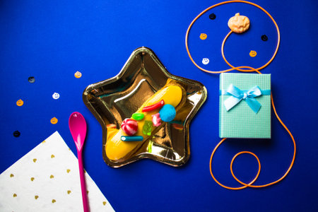Halloween dessert. Yummy eclair on gold star shaped plate, pink spoon, napkin with hearts, gift box...