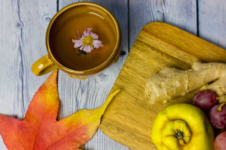 Autumnal still life - bunch of grapes, ripe quince, ginger root lie on wooden cutting board top...