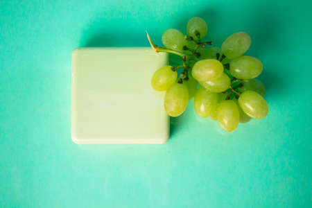 Handmade soap bar with grape scent. A bunch of green grapes. Grape extract in skin care cosmetics for face, body. Spa procedures, treatments concept. Zero wast organic eco cosmetic natural ingredientsの写真素材