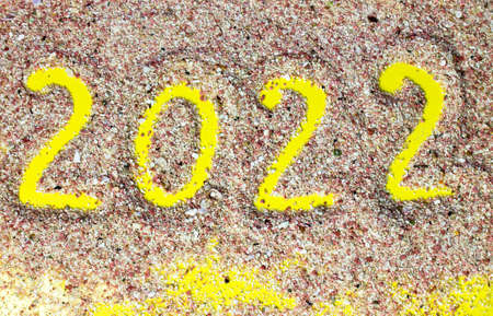 Text 2022 written on pink sand on a seashore beach top view. Happy New Year and Merry Christmas celebration Concept. Trip, travel on winter holidays abroad. Natural yellow backdrop. Summer destinationの写真素材