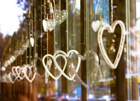 Heart-shaped led garland is hanging on a window. Many white hearts on a wire decorate the interior in the holiday of St. Valentine's Day. 14th February. Declaration of love concept. Home Decorations.の写真素材