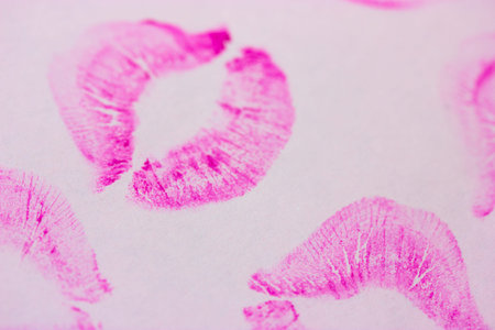 Beautiful shape pink female lip prints on white paper background top view. Kisses flat lay. Lipstick...