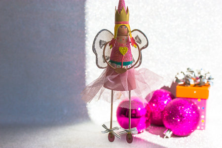 Toy fairy in pink dress with crown on head and wings holding magic wand with heart image in hands. Girl angel princess doll toy for little girls on white background. New year 2022 winter holidays fun.の写真素材