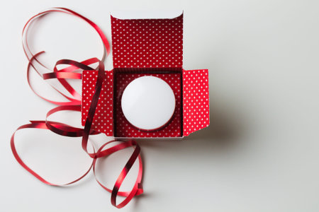 Christmas present in red box with jar of cream on white background with space for text top view....