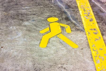 Yellow pedestrian lane, permit sign. Road walk markings on asphalt. A yellow man sign and line on a flour, ground. Walking area. Infrastructure. A sidewalk for walking, moving people on a city street.の写真素材