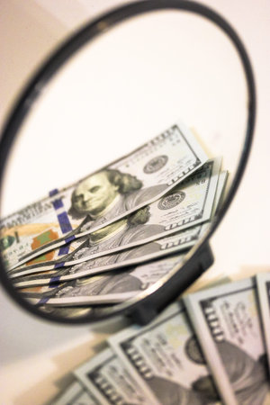 Hundred US dollar bills, cash lie on white table, reflected in round mirror. Earnings, profits,...