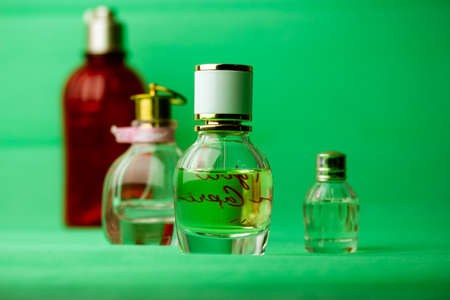 Different bottles of eau de toilette perfumes fragrances on green background. Cosmetic essential oil in bottles, jars. cosmetics for beauty care. Set of vials, aroma oils for aromatherapy. Body Lotionの写真素材