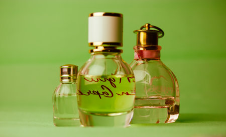 Kiev, Ukraine. May 1, 2021. Glass bottles of eau de toilette, perfumes, fragrances on green background. Cosmetic essential in bottles, jars. Beauty care. Set of vials for perfume. Smells for women.のeditorial素材