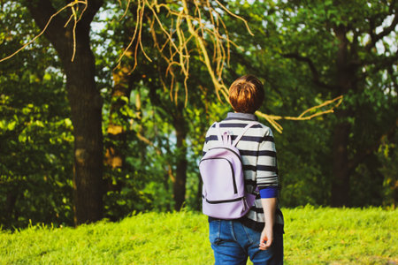 Free time leisure. Walking in nature. Woman with a short haircut and a backpack behind her back...