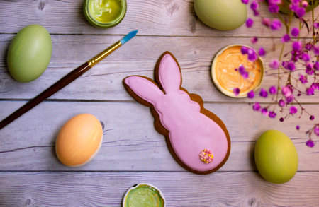Festive Easter composition with colorful green, yellow eggs, paint brush, Easter bunny lying on...