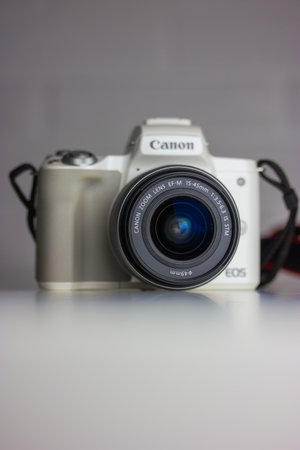 Kyiv, Ukraine. January 7, 2022. White digital mirrorless 4K camera Canon EOS M50 with black lens on white background. Mirrorless Vlogging Camera Kit with EF-M 15-45mm Lens for photographer. vertical.のeditorial素材