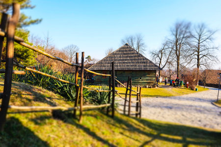 Uzhgorod, Ukraine. March 1, 2021. Ukrainian village with traditional thatched roof houses. Ethno museum in the open air. cultural heritage. An old wooden fence and green grass on a sunny spring day.のeditorial素材