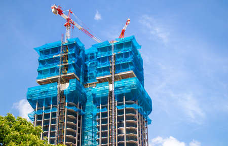 Two multistory buildings, facade is covered with protective construction mesh.の写真素材