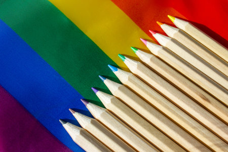 A set of wooden multicolored pencils against a rainbow abstract background. All colors of the...