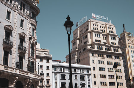 Madrid, Spain, May 7, 2022. Tall, modern, houses in business district in a center of metropolis buildings. urban scene. Spanish architecture against blue sky with cinematic effect. cityscape postcard.のeditorial素材