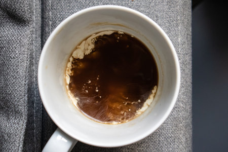 White cup, mug with black coffee and milk on gray-blue textile surface top view. Hot aromatic coffee...