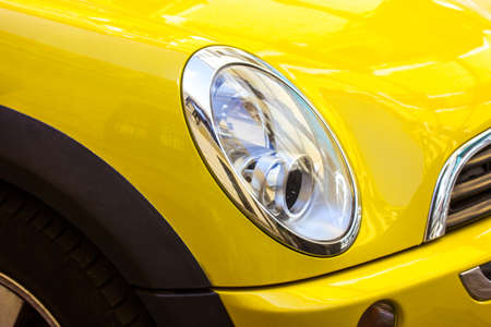 Madrid, Spain. June 7, 2022. Oval front headlight of modern stylish yellow car. Sedan automobile MINI Cooper Countryman up close. Automotive business. Licensing, driving lessons, road travel concept.のeditorial素材