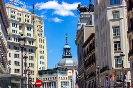 Madrid, Spain. June 1, 2022. Ancient old vintage architecture in a modern city center. Universal bank building, hotel sign, road signs in urban scene. A dome of a church on a horizon against blue sky.のeditorial素材