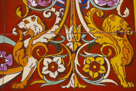 Madrid, Spain. June 1, 2022. Beautiful decorative ceramic tiles with lions, flowers on a red terracotta background. Traditional Spanish symbols. Mosaic backdrop. Fragment of vintage orange tile art.のeditorial素材