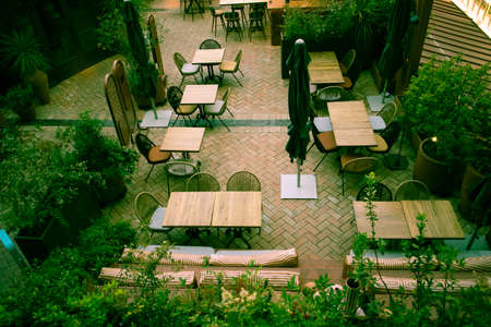 Madrid, Spain. June 1, 2022. Summer outdoor terrace of cafe, restaurant, boutique hotel in summer. Lots of empty tables, chairs on cozy seating area with green plants view from above. garden furnitureのeditorial素材