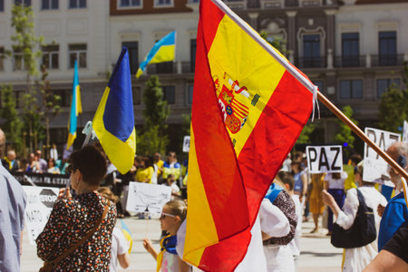 Madrid, Spain. May 8, 2022. People at rally in support of Ukrainians affected by Russia. Patriots with yellow blue Ukrainian flags and Spanish flag. Global Boycott, Stop Putin concept. Support Ukraineのeditorial素材
