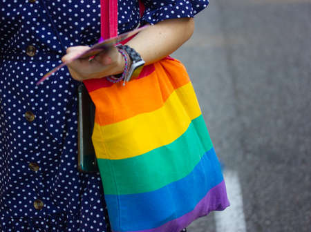 A woman or girl in a black dress with white polka dots and a multicolored striped bag in rainbow colors. Symbol of the LGBT community. Lesbian, bisexual, gay on Pride Month. Photo for blogs space for textの写真素材