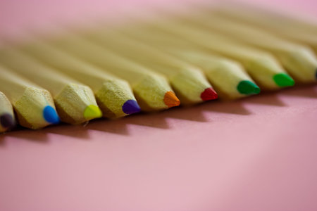Multicolored wooden pencil rods macro photo on pink table background. Tools for creativity, drawing,...