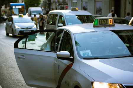Madrid, Spain. July 1, 2022 A white cab service car on a city street. Transportation of passengers. Automobile with open door while passenger is boarding. Taxi in urban scene on a road. urban traffic.の写真素材