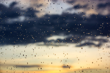 Raindrop background. Overcast weather, rain on a sunny day. Glass surface dotted with lots of small...
