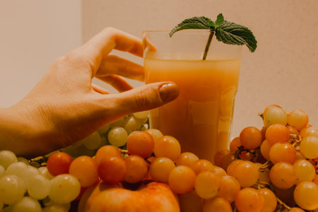 Woman's hand reaching for a glass of freshly squeezed fruit juice of various seasonal tropical...