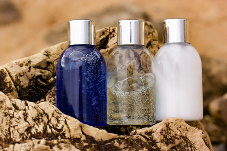 Plastic bottles with natural cosmetic in travel containers - blue shower gel, shampoo with bubbles...
