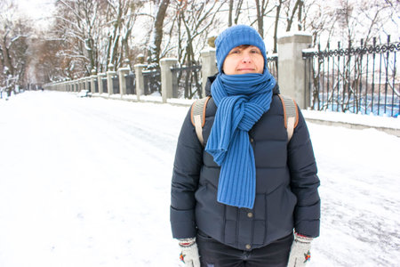 Young European woman 30-40 years old looking smiling into camera standing in snow-covered winter...