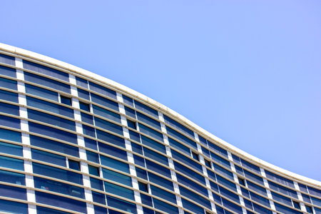 Modern gray high rise office building facade with glass windows in business center, neighborhood, city district. Skyscrapers in the urban space. corporate against sky. flowing lines in architecture.の写真素材